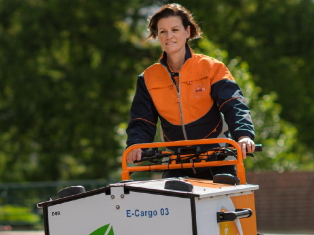 Eleketrische bakfiets Post NL met vrouw aan het stuur 