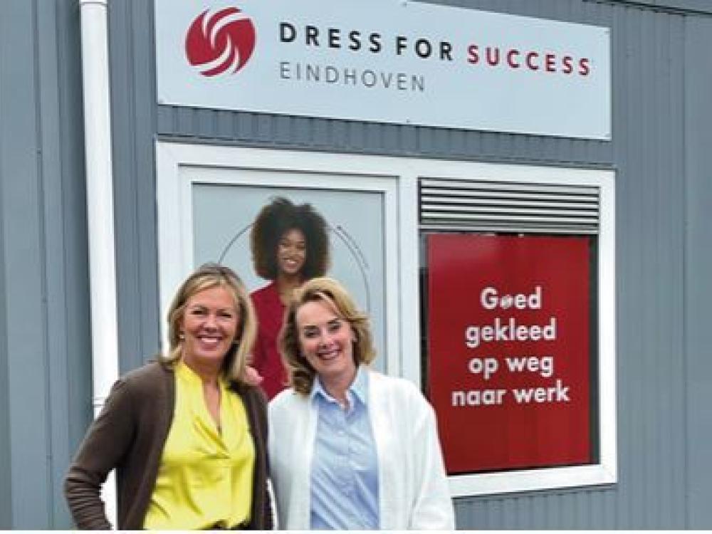 Twee dames voor de winkel van Dress for Succes. Slogan: Goed gekleed op weg naar werk