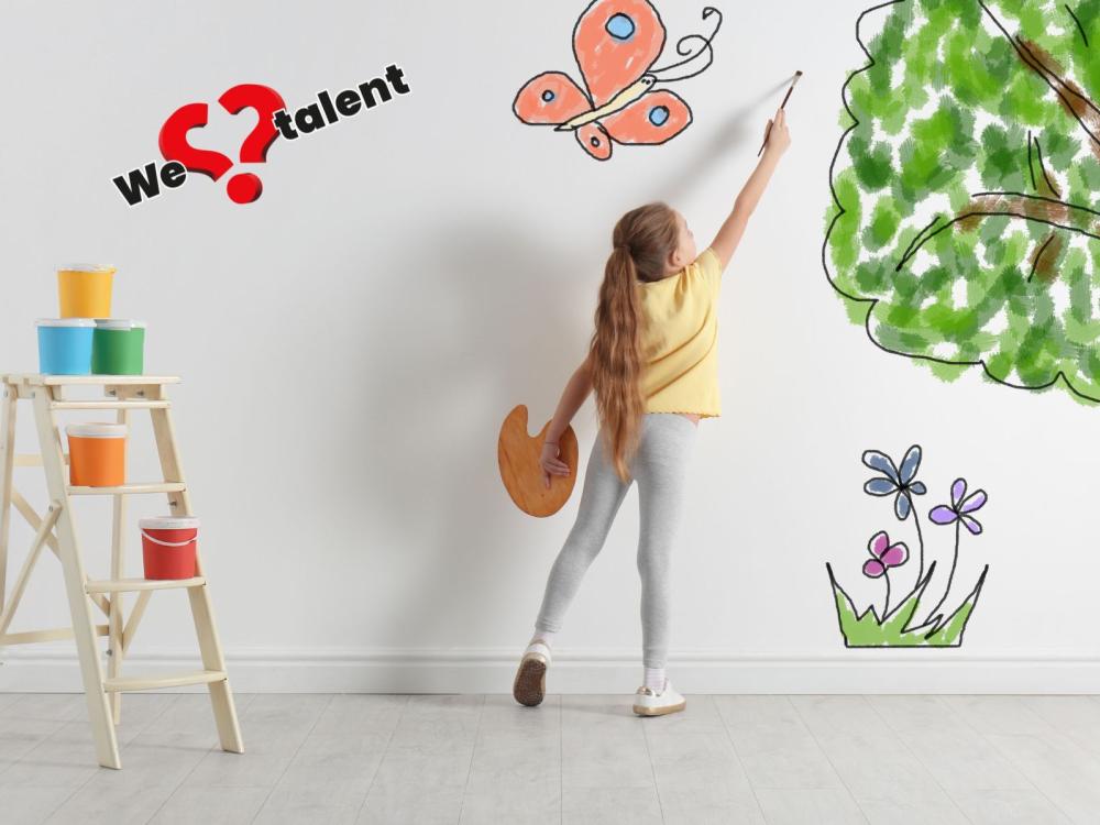Meisje schildert op wand, met tekst we love talent
